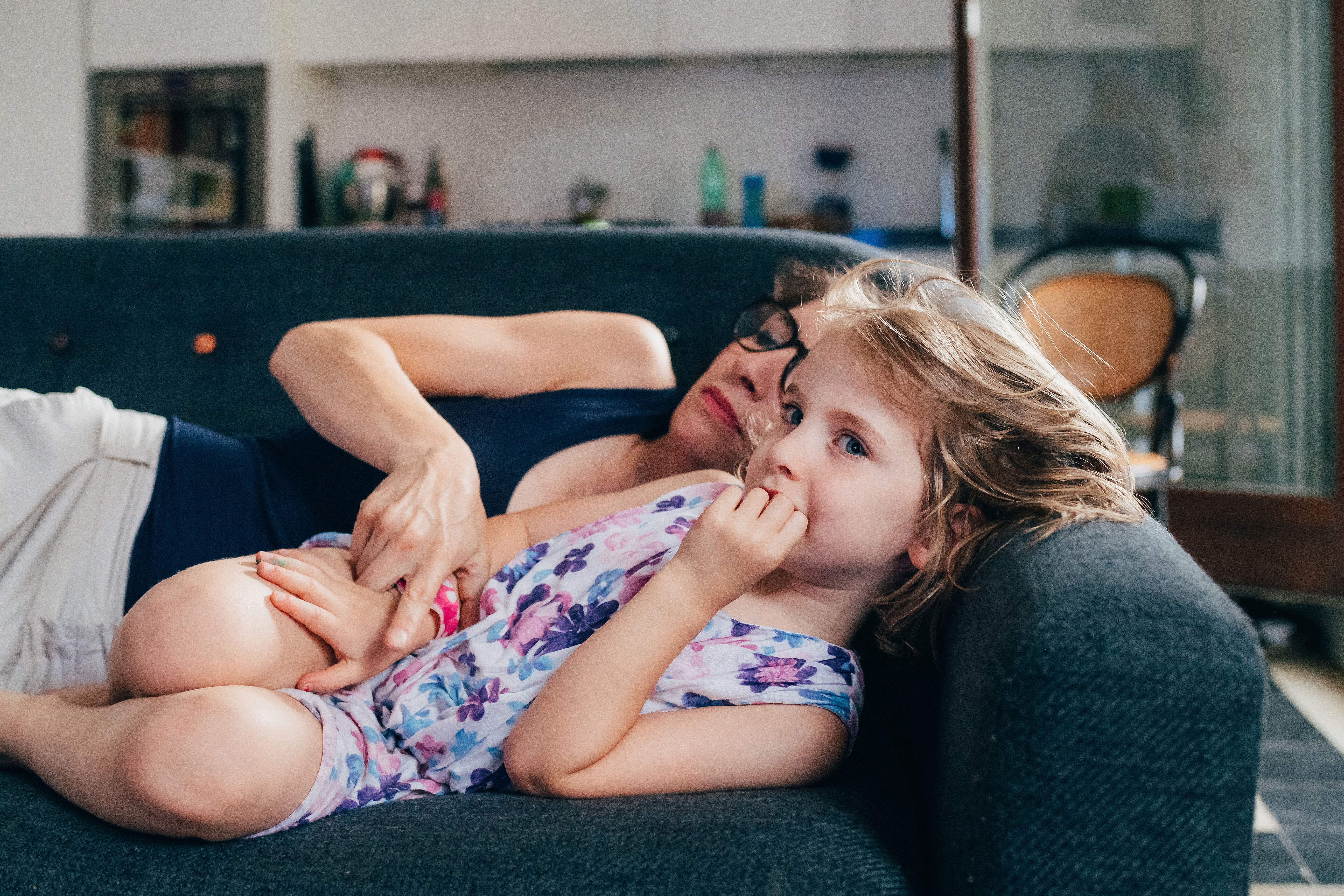 Mother with female child indoor on the couch cuddling - comforting, love, bonding concept